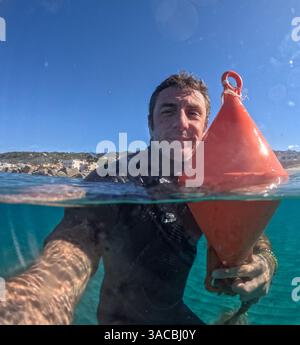 Stopping a buoy while swimming in the Mediterranean Sea Stock Photo