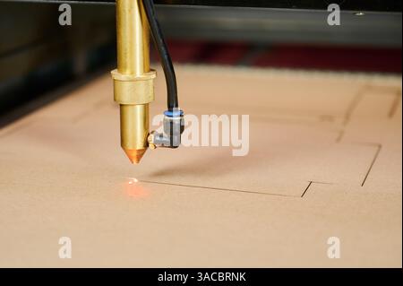 Precision laser cutting crafts cardboard shapes in a busy manufacturing plant during daylight hours Stock Photo