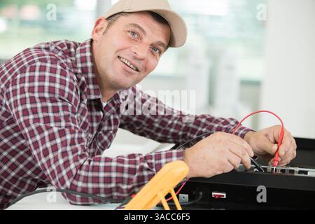 happy technician man using screwdriver and digital multimeter Stock Photo
