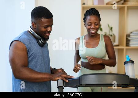 Smiling Couple Exercising on Treadmill in Modern Gym Stock Photo