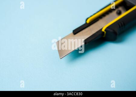 Top view of yellow and black utility knife on blue background Stock Photo