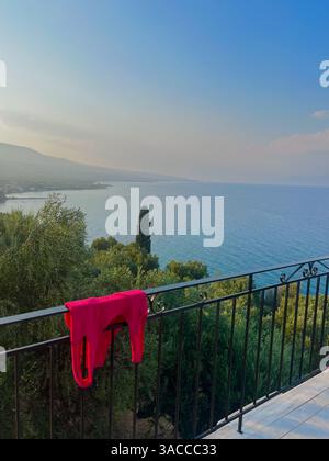 Oceanview from balcony in Greece-Crete with a Beautiful sunset sky. Colorful laundry drying on an outdoor clothesline on a house balcony next to the Mediterranean Sea. High quality photo Stock Photo