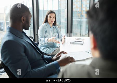 Portrait of successful disabled businesswoman in wheelchair leading meeting with diverse business team in office Stock Photo