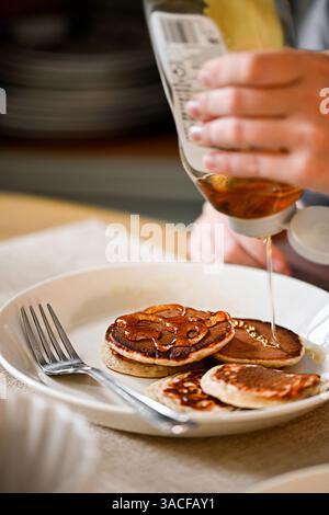 Pouring honey over homemade pancakes in a plate, home cooking Stock Photo