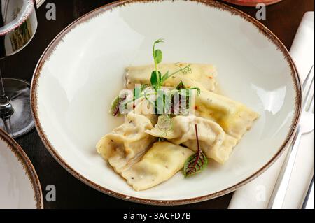 ravioli with sauce and herbs on a white plate Stock Photo