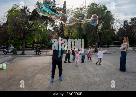 A street entertainer blowing big bubbles for children in the National Garden, Athens, Greece Stock Photo