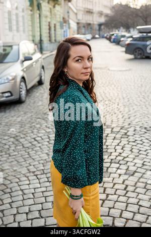 Serious woman standing on cobblestone street in city Stock Photo