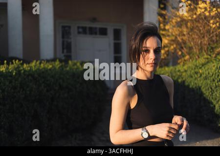 Stylish Young Woman in Black Outfit Standing Outdoors Stock Photo