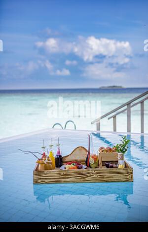 Breakfast in swimming pool, floating breakfast in luxurious tropical resort. Table relaxing on calm pool water, healthy breakfast and fruit plate Stock Photo