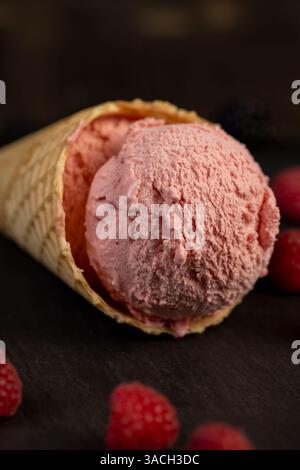 ice cream with red raspberry berries on a black slate board, close up of berry flavored ice cream with fresh raspberries and blackberries Stock Photo