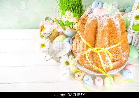 Easter sweets and decorations background, Sweet easter cake panettone with colorful painted eggs, spring grass and decor, copy space for text Stock Photo