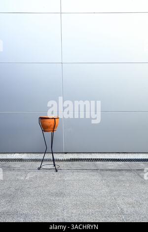 Retro style Clay pot Ashtray in front of wall made from light blue synthetic materials on modern building. Stock Photo