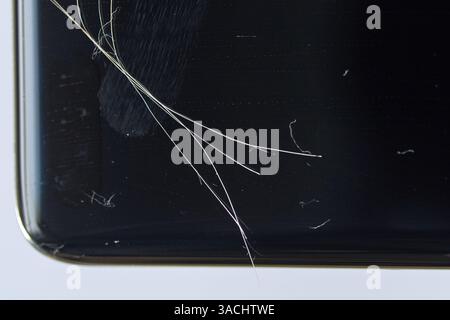 Close up of a cracked smartphone screen with visible scratches and dust on black surface. Stock Photo