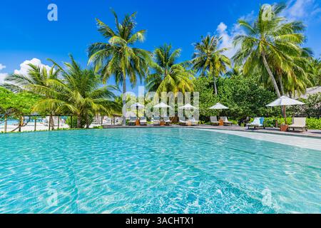 Amazing vacation tourism. Beautiful luxury umbrella chairs around outdoor swimming pool in hotel and resort with coconut palm tree sunny sunshine sky Stock Photo