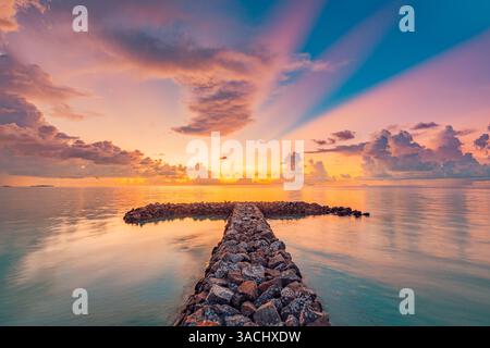Tranquil sea sunset breakwater. Sun rays over rocks with horizon and endless ocean view. Calm nature scene, beach landscape, positive thinking inspire Stock Photo