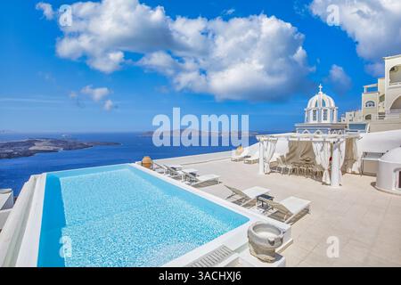 Luxury hotel view of caldera and swimming pool in foreground, white architecture on Santorini island, Greece. Summer vacation romantic background Stock Photo