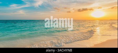 empty panoramic sunset beach with golden skies reflecting on calm waters, stretching along a serene coastline perfect for peaceful escapes and sunse Stock Photo