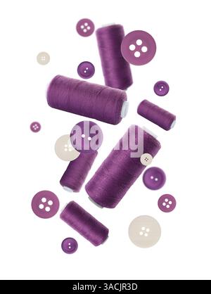 Many purple sewing threads and buttons falling on white gradient background Stock Photo