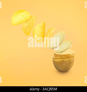 Raw potato slices transforming into crispy chips in air on pale orange background Stock Photo