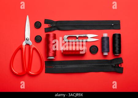 Different sewing supplies on red background, flat lay Stock Photo