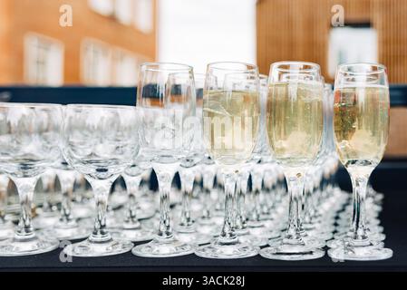 Rows of champagne and wine glasses arranged on a table for a festive outdoor celebration or formal event gathering. Stock Photo