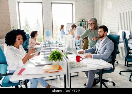 Collaborative team working in modern office interior with bright lighting during daytime, colleagues discussing projects Stock Photo