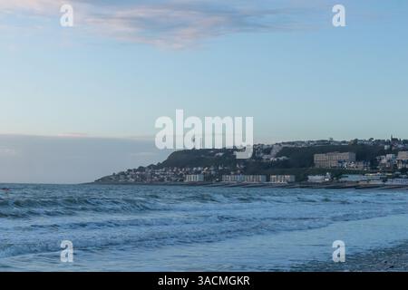 Le Havre, France, February 26, 2025: The high cliffs of Normandy rise above the sea in Le Havre, glowing with the last light of sunset as twilight wra Stock Photo