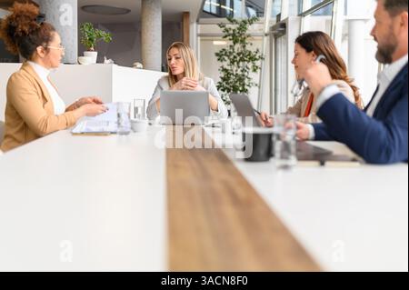 Female lawyer discussing legal strategies with teammates and collaborating on case details in meeting Stock Photo
