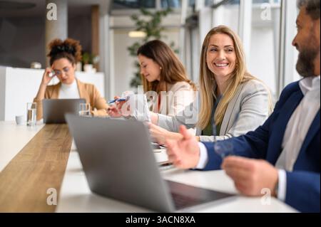 Professional colleagues smiling and discussing project details while working together in meeting room Stock Photo
