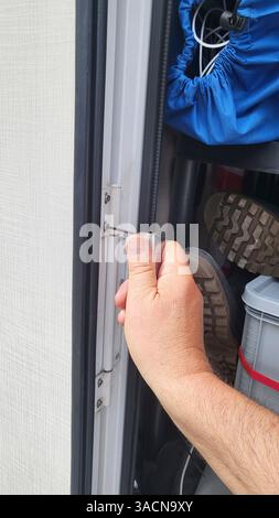 Craftsman uses an Allen key to tighten the hinges of a motorhome door. Stock Photo