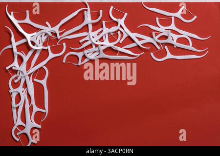 Image of white interdental toothpicks with a thread on a red background in the upper left corner of the frame. Stock Photo