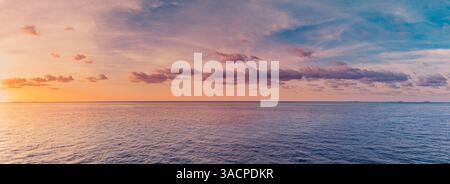 Sea sunset panorama vibrant sky clouds colors reflecting on water, endless dreamy horizon, serene glow over calm ocean. Seascape skyline wallpaper Stock Photo