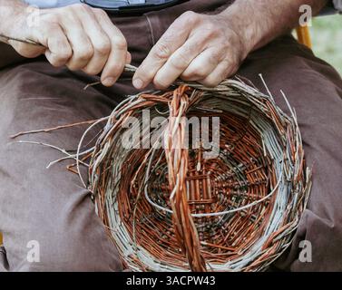 Close up of craftsman's hands weaving wicker basket, showcasing traditional craftsmanship and handiwork Stock Photo