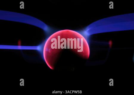 Pink and blue plasma filaments extending from a central sphere, creating a mesmerizing display of light and energy Stock Photo