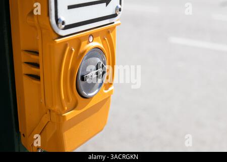 Push to walk button at intersection. Well used worn crosswalk button to activate traffic light in city. Blind and deaf-friendly sign. Selective focus. Stock Photo