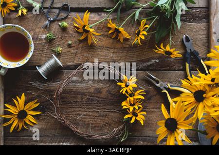 Overhead shot of wreath making with yellow flowers on rustic wooden table Stock Photo