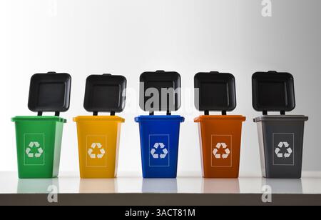 Row of open plastic recycling bins with multi-colored recycling symbol on white reflective base and white isolated background. Front view. Stock Photo