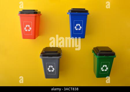Set of multi-colored recycling bins with multi-colored recycling symbol isolated on yellow base. Top view. Stock Photo