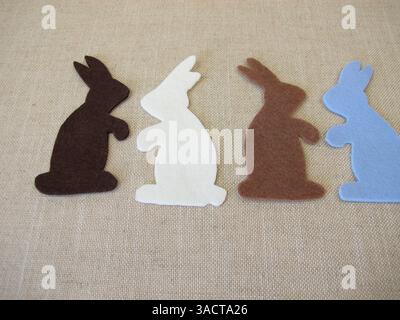 Four Easter bunnies cut out of colored felt with scissors for Easter Stock Photo