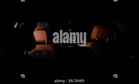 Empty car interior at night showing infotainment system displaying a 3d model of the car itself, with brown leather seats Stock Photo