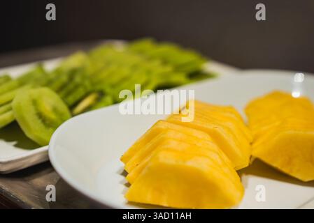Close Up of Pineapple and Kiwi Slices on White Plates Stock Photo