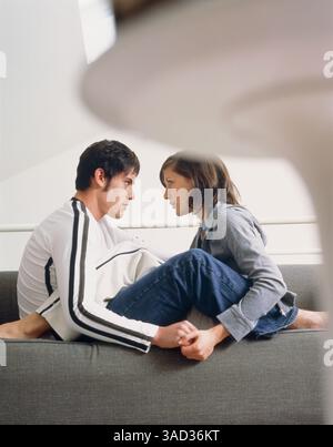 Young couple sitting on a couch face to face Stock Photo