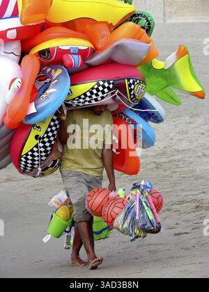 Flying merchant, seller overloaded with large quantities of beach toys ...