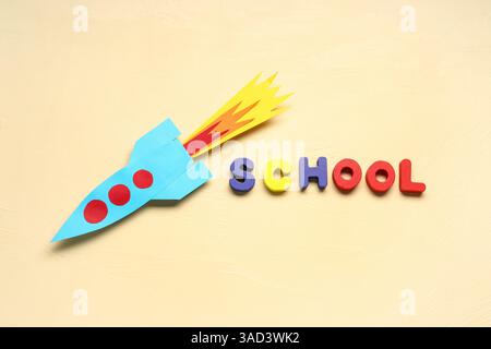 Paper rocket with word SCHOOL on beige background Stock Photo