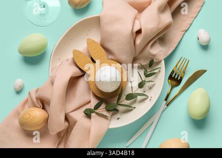 Beautiful table setting with Easter eggs and eucalyptus branch on turquoise background Stock Photo