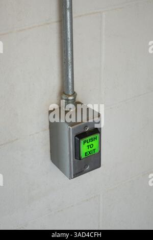 Illuminated green push to exit button on wall Stock Photo