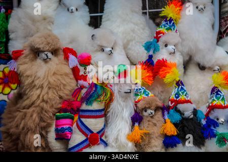 Colorful peruvian textile souvenirs sold at the local tourist market. Woman sell Peruvian traditional craft dolls and clothes made from alpaca wool Stock Photo