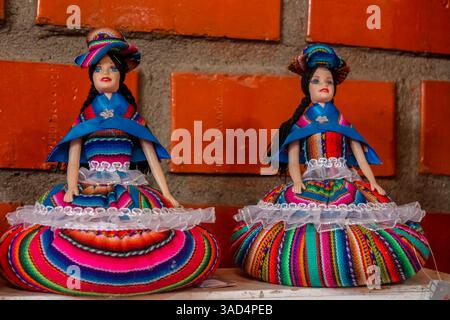 Colorful peruvian textile souvenirs sold at the local tourist market. Woman sell Peruvian traditional craft dolls and clothes made from alpaca wool Stock Photo