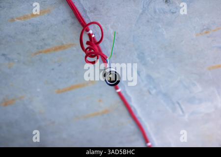 This image features a closeup view of a bright red wire placed on a textured concrete surface, showcasing its vibrant color clearly Stock Photo