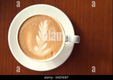 Coffee Latte with milk foam on brown table at cafe Stock Photo